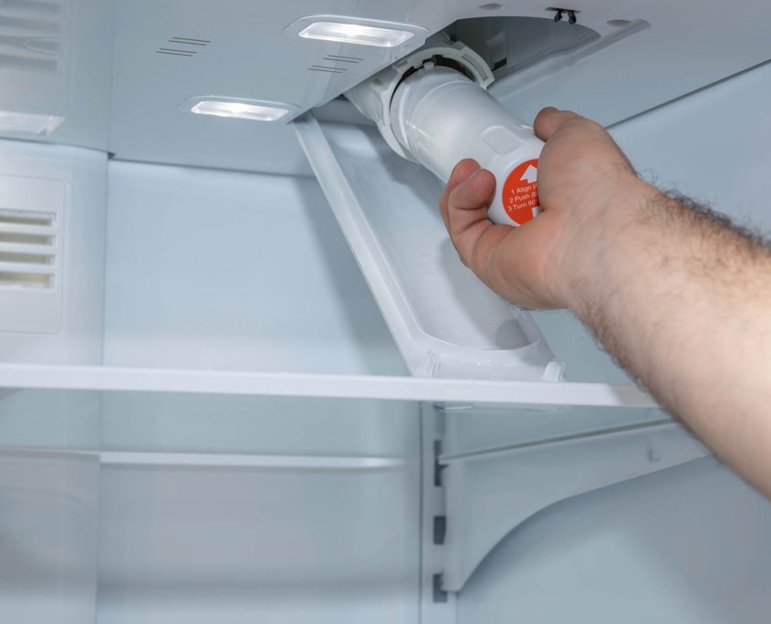 Person changing out filter in refrigerator