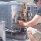 HVAC technician working on controls of air conditioner