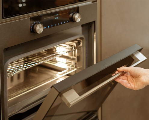 Woman hand opening built-in oven in black kitchen cabinet