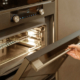 Woman hand opening built-in oven in black kitchen cabinet