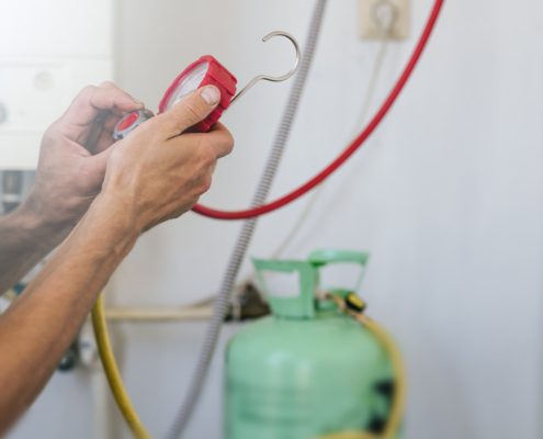 Hands of professional working with refrigerant tank and connecting hoses