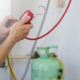 Hands of professional working with refrigerant tank and connecting hoses