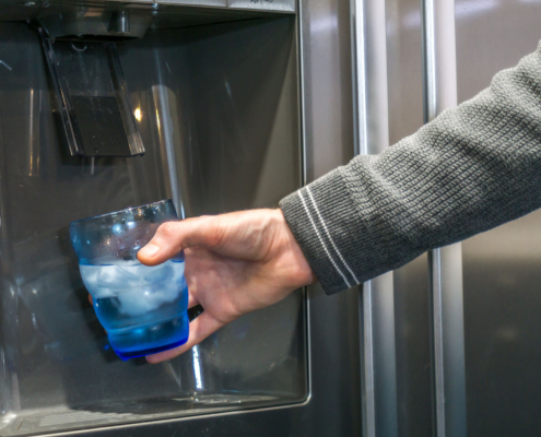 person using the ice machine on fridge