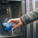 person using the ice machine on fridge