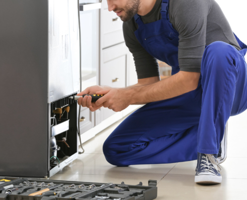 Male technician repairing refrigerator indoors