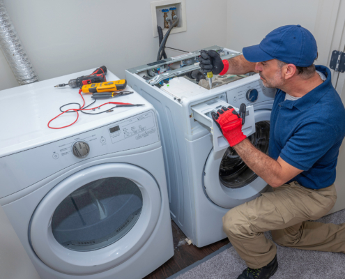 Side view of repairman working on washer and dryer units